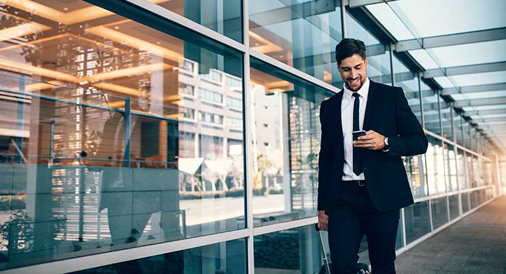 Man in suit rolling suitcase